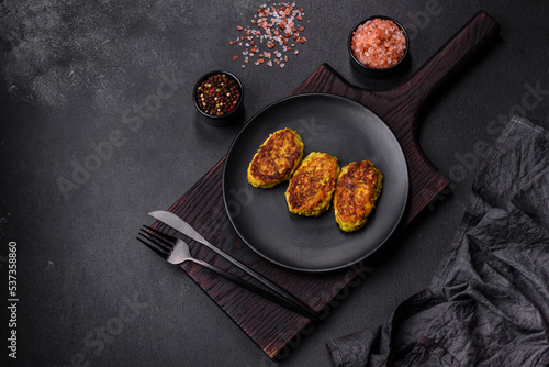 Diet vegetable cutlet from zucchini, carrot, herbs on a black plate