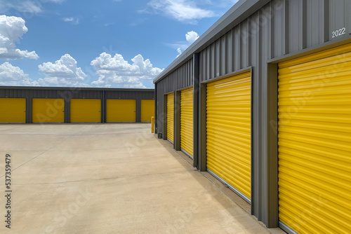 Outdoor shot of warehouses, storage facility, hangars or garages with yellow rolling gates