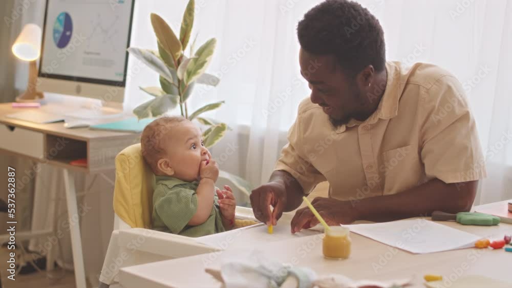 Caring African American father cleaning high chair after feeding his cute baby son at home Caring African American father cleaning high chair after feeding his cute baby son at home