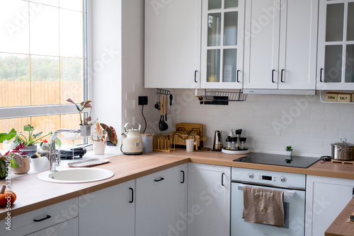White cozy kitchen in Scandi loft style. Home interior, dining room design, oven, hob, table, kitchen furniture