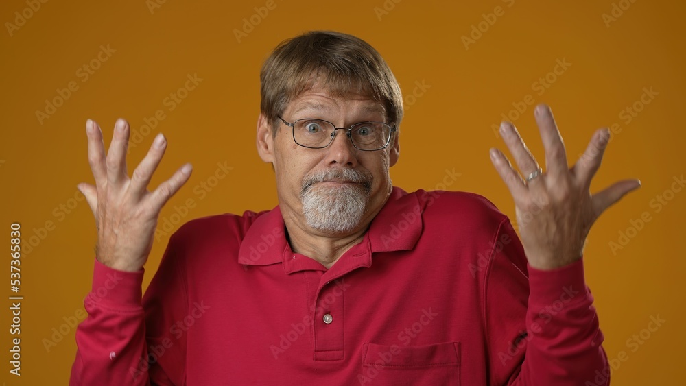 Mature man unsure guy in red shirt shrugs his arms, makes gesture of I dont know, cant help anything isolated on solid yellow background. Mature man unsure guy in red shirt shrugs his arms, makes gesture of I dont know, cant help anything isolated on solid yellow background.