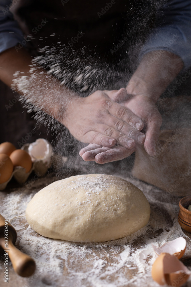 Obraz premium Baker chef man sprinkling flour at dough bread and bakery ingredients for homemade cooking on table