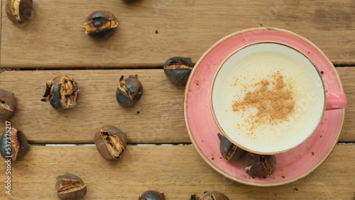 Salep and chestnuts in pink coffee mug on wooden table. Advertising flyers photo