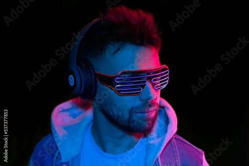 the concept of music. A yought man listens to music with headphones on against a black background