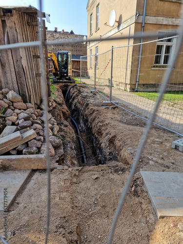 Street and sewer pipes repair in summer day. Sand, fence and houses. photo