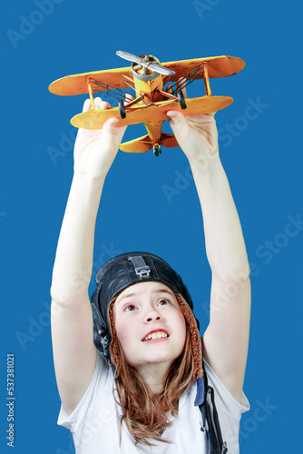 Young girl-pilot against the blue sky. A symbol of travel and development - a teenager dreams of flying. Girl with a toy plane