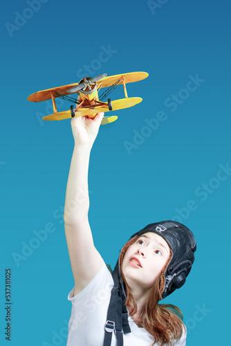 A symbol of travel and development - a teenager dreams of flying. Girl with a toy plane. Young girl-pilot against the blue sky