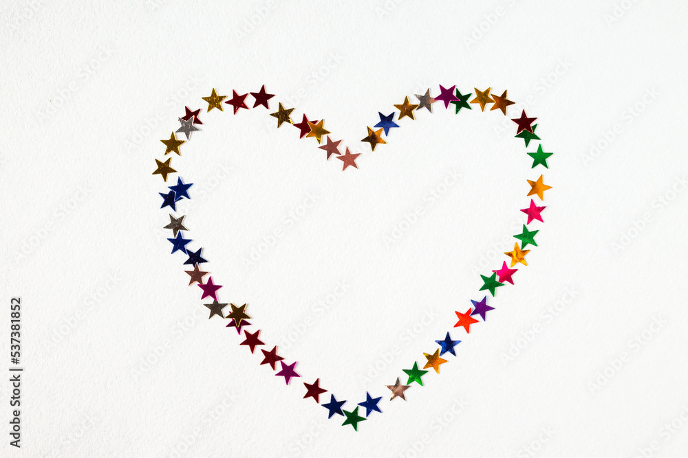 confetti laid out in the shape of a heart on a white background, copy space