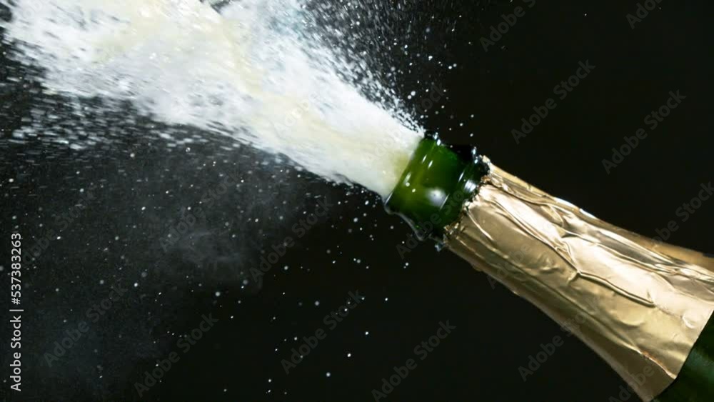 Super slow motion of Champagne explosion with flying cork closure, neon colors, opening champagne bottle closeup.