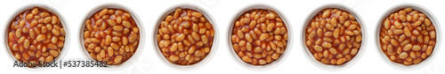 Baked beans in tomato sauce in a white ceramic bowl isolated on white. Top view.