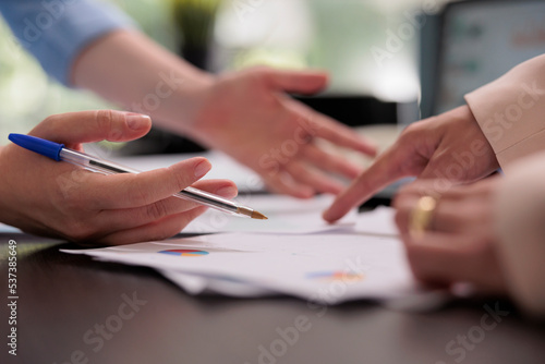Coworkers analyzing financial report on meeting, planning company budget, close up on hands, woman pointing on charts. Colleagues teamwork, start up project investement briefing concept