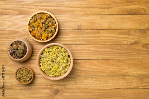 Different herbs in bowls on wooden background, top view