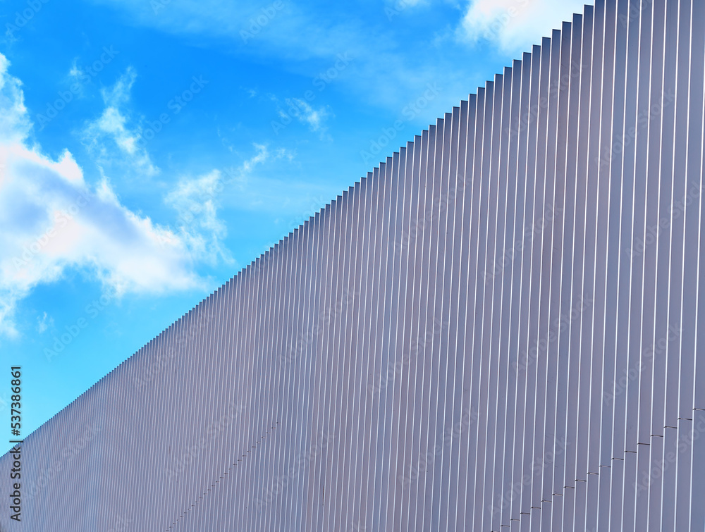 Blue sky clouds over diagonal fence backdrop