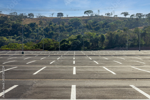 Big parking lot completely empty with hill covered by vegetation in the background
