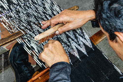 Close up of traditional weaving technique IKAT for making scarfs or Makana (macana) or other fabric by hand with cotton threads. Design are traditional for Gualaceo canton, Azuay province, Ecuador photo