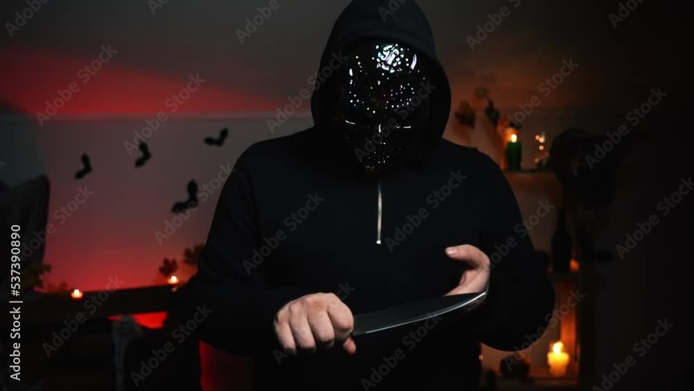 Man in a scary mask with a metal knife in his hands Man in a scary mask with a metal knife in his hands