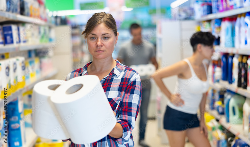Young caucasian woman choosing paper towels roll in supermarket.