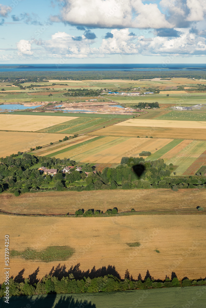 Obraz premium Rural landscape from a hot air balloon. Lithuanian agricultural fields in the early morning. Vertical photo
