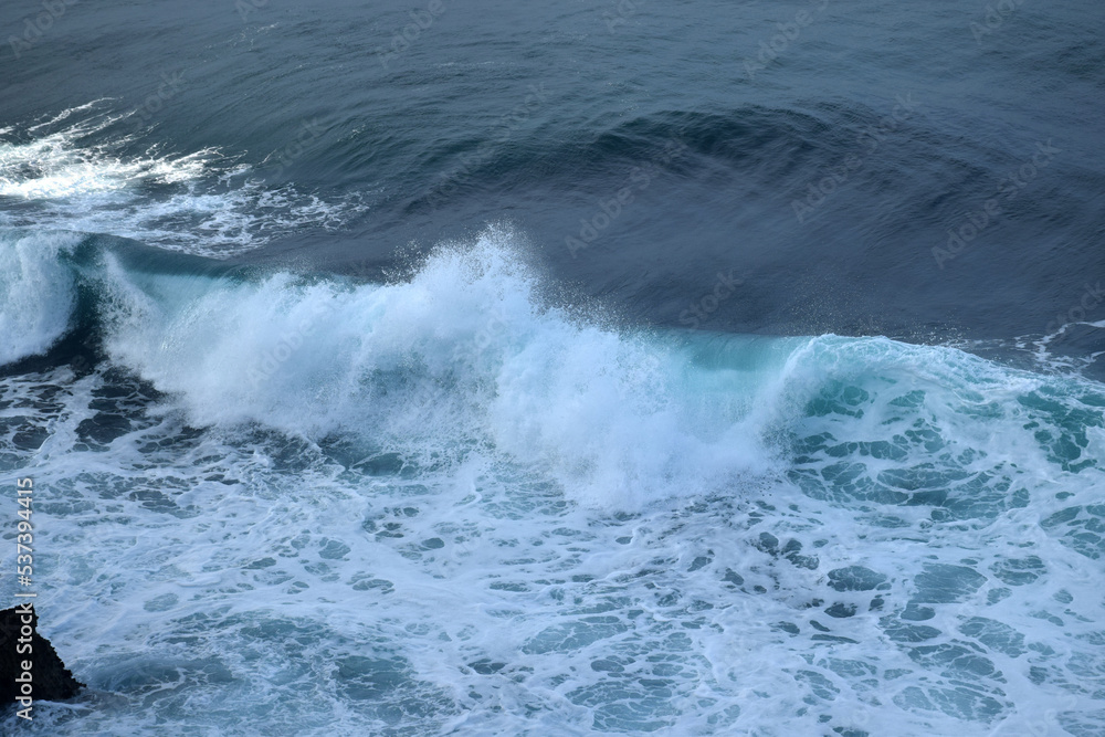 The waves crashing in the ocean, with a bluish tint at Drini Beach, Gunungkidul, Yogyakarta The waves crashing in the ocean, with a bluish tint at Drini Beach, Gunungkidul, Yogyakarta