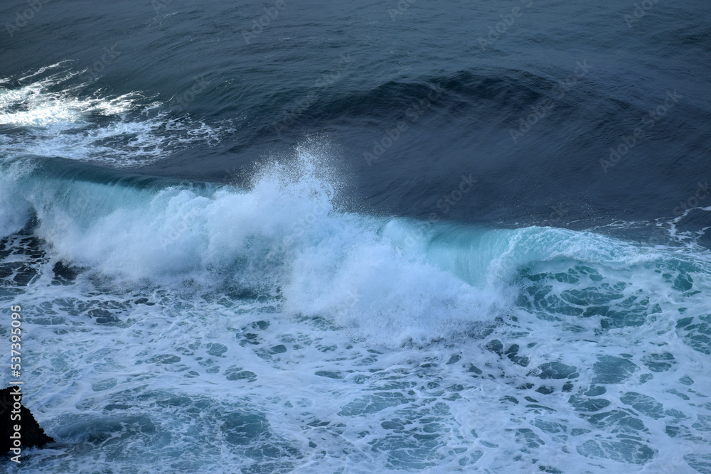 The waves crashing in the ocean, with a bluish tint at Drini Beach, Gunungkidul, Yogyakarta The waves crashing in the ocean, with a bluish tint at Drini Beach, Gunungkidul, Yogyakarta