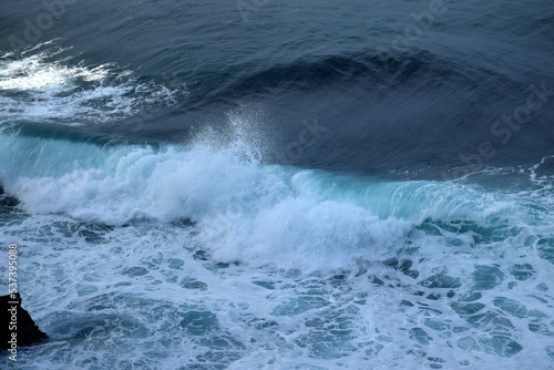 The waves crashing in the ocean, with a bluish tint at Drini Beach, Gunungkidul, Yogyakarta