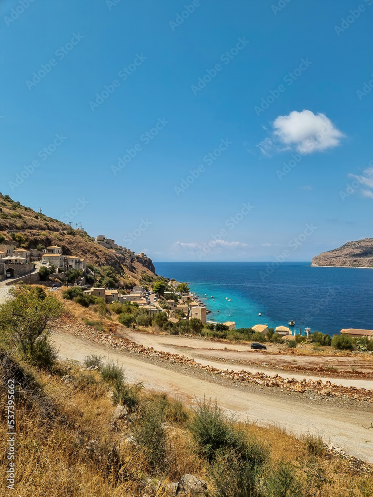 view of Limeni village with fishing boats in turquoise waters and the stone buildings as a background in Mani, Greece.