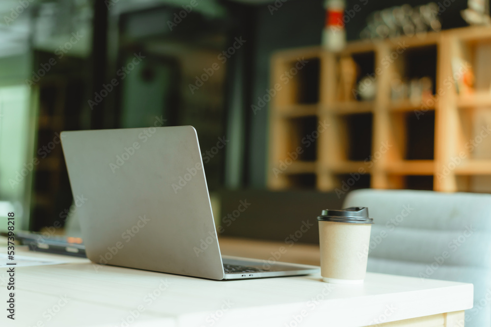 Modern workspace laptop and notebook on white table with blurred office room background. Modern workspace laptop and notebook on white table with blurred office room background.