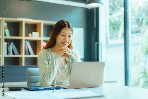 Beautiful young Asian businesswoman working at workspace.