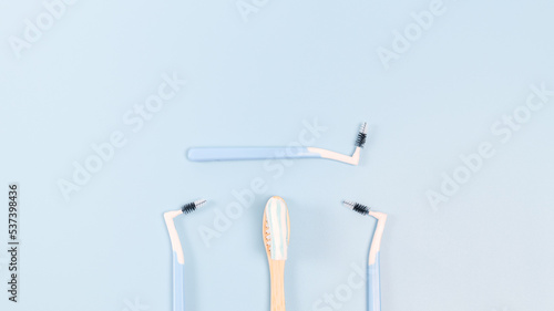 Bamboo toothbrush with toothpaste and three small toothbrushes on a soft blue background © Nataliya