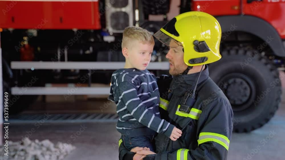 Portrait of firefighter with cute boy on arms. Concept of saving lives, fire safety Portrait of firefighter with cute boy on arms. Concept of saving lives, fire safety
