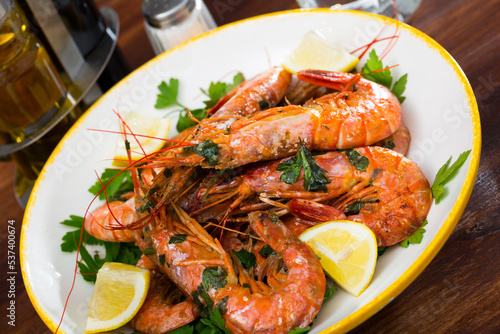 Seafood appetizers, roasted prawns served with parsley and lemon slices