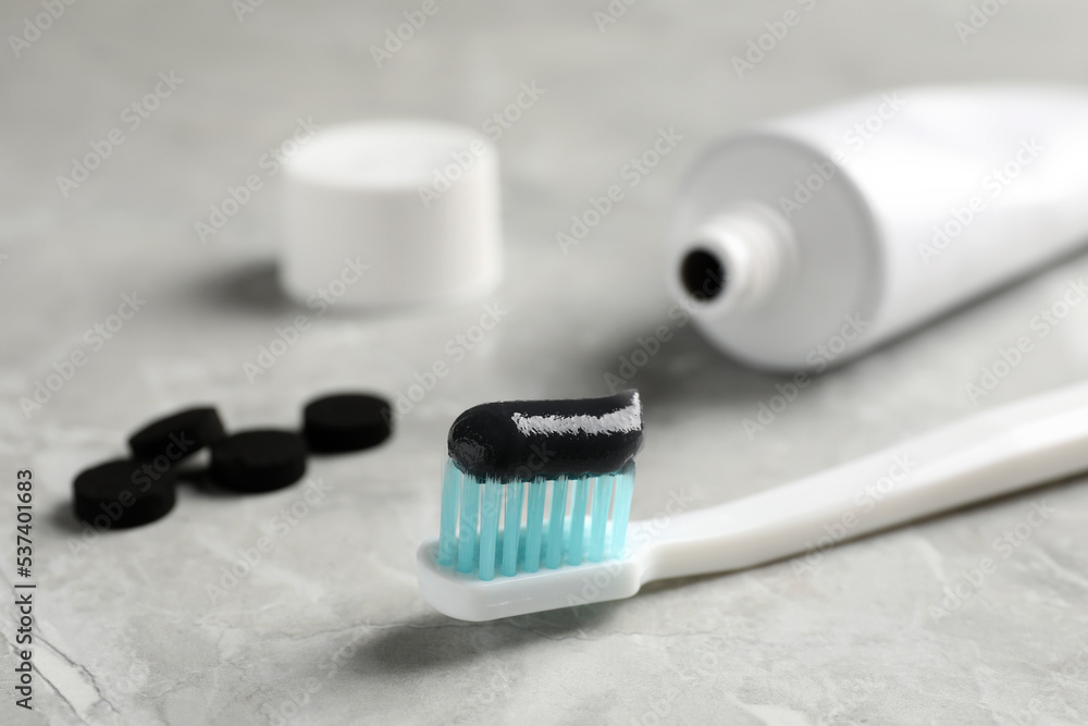 Brush with charcoal toothpaste on light grey table, closeup Brush with charcoal toothpaste on light grey table, closeup