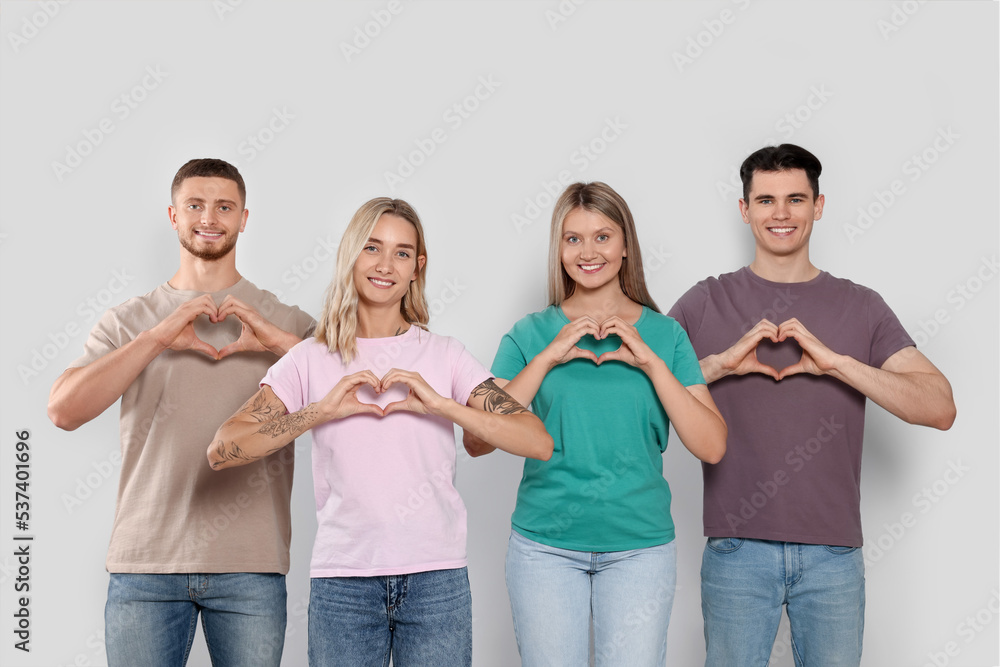 Obraz premium Happy volunteers making hearts with their hands on light background