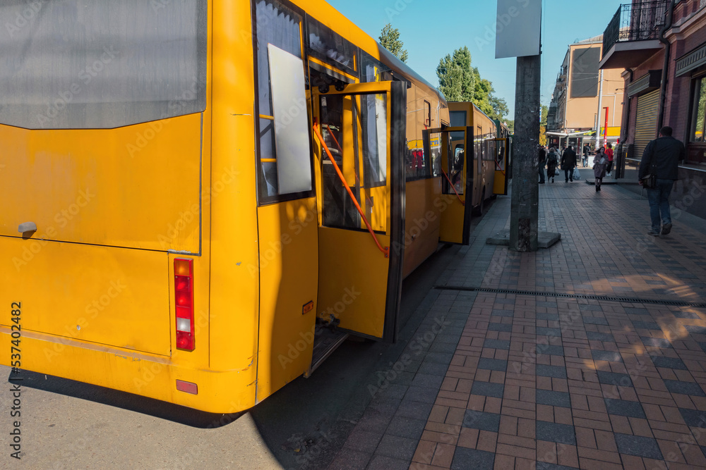 Modern yellow city buses with open doors on the city's street. Facility. Transfer. Carry. Movement. Moving. Drive. Avenue. Environment. Highway. Way. Lane. Roadway. Service. Station