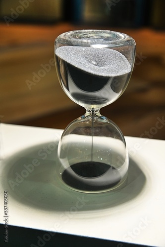 Sand running through the bulbs of an hourglass that measures the passing time in a countdown to a deadline, on a blurred background