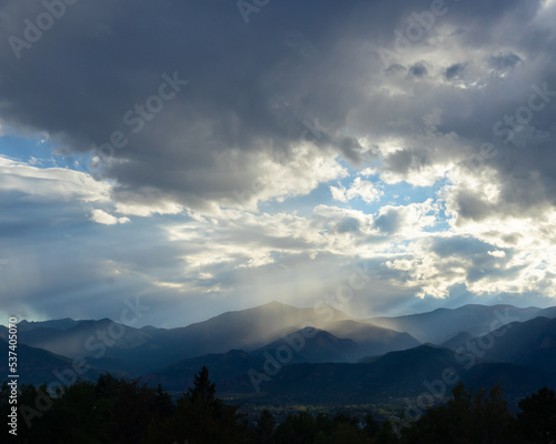 Landscape photograph with dramatic storm clouds raining on dark hills. 