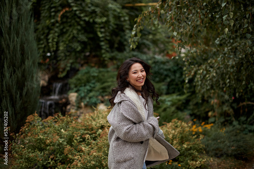 Portrait of pretty asian kazakh brunette woman with charming smile walking along outdoors