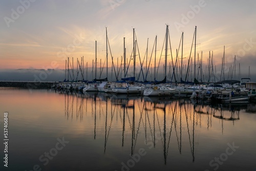 Fototapeta Naklejka Na Ścianę i Meble -  Sailboat reflections in a misty pink sunrise