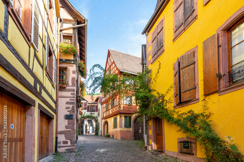 A picturesque street and alley of half-timbered medieval buildings in the historic center of Kaysersberg-Vignoble, France, in the Alsace region.