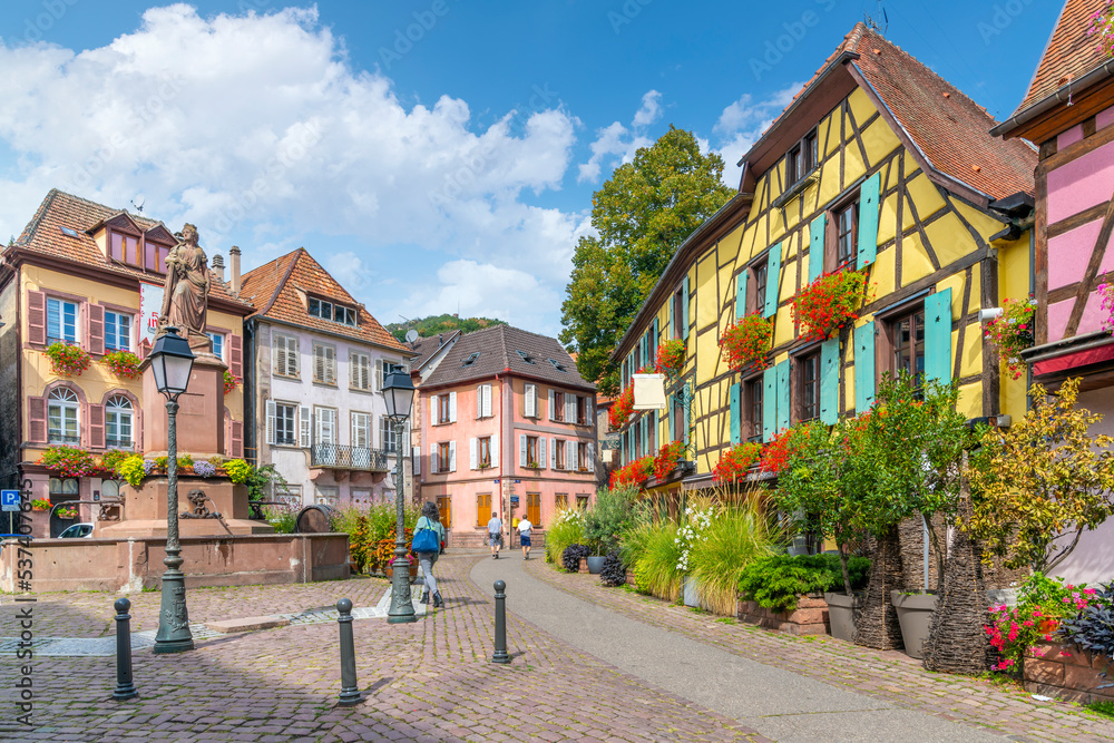One of the many picturesque and colorful streets and alleys of half-timbered buildings in the medieval village of Ribeauville, France, in the Alsace wine region of France at Place de la Sinne Square.