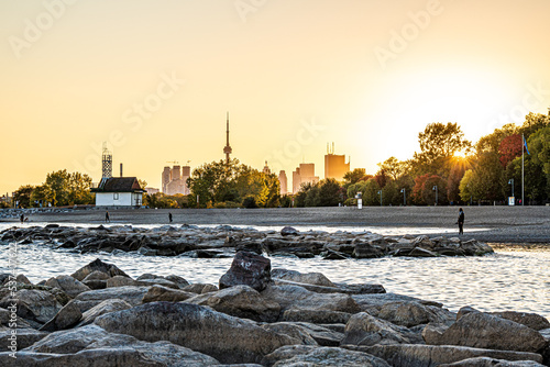 Photography Evening walkers enjoy the Toronto Beaches lit up up an October sunset with the cranes of downtown construction in the background