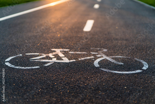 Quadro su tela bike path with sunset sun, bicycle sign on asphalt