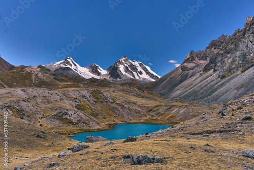 Paisaje de montañas con vegetación y glaciares rodeando laguna color turquesa 