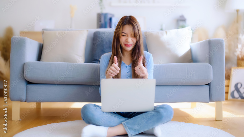 Young asian woman working on her laptop at home, grinning. attractive Asian woman utilizing computer for online schooling, video calling, and conference calls Young asian woman working on her laptop at home, grinning. attractive Asian woman utilizing computer for online schooling, video calling, and conference calls