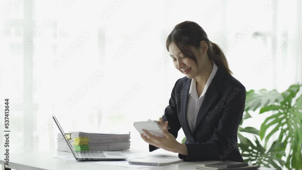 Asian female accountant working on financial chart analysis with laptop and smartphone. Asian female accountant working on financial chart analysis with laptop and smartphone.