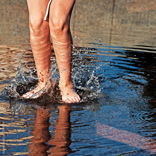 A child jumps in a puddle on the street after a rain. Legs of a jumping child close-up.