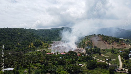 Plumes of smoke from fire burning rubbish at landfill on the outskirts of capital Dili, Timor Leste, Southeast Asia, aerial drone view of landscape