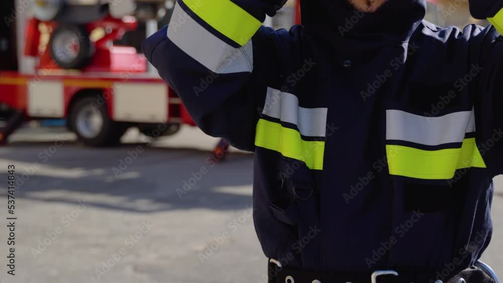 Fireman with helmet near fire engine. Concept of saving lives, heroic profession, fire safety Fireman with helmet near fire engine. Concept of saving lives, heroic profession, fire safety