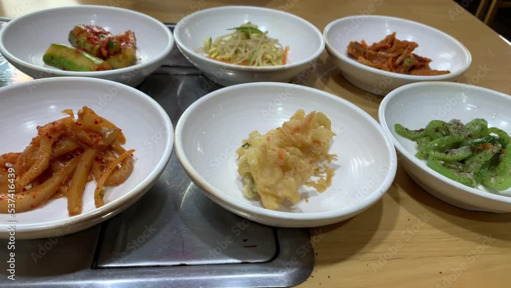Traditional Korean food with small side dishes called banchan in a restaurant. Top view panning shot. Traditional Korean food with small side dishes called banchan in a restaurant. Top view panning shot.