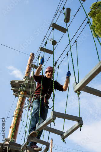 A man is resting in a rope amusement park. Vertical photo.